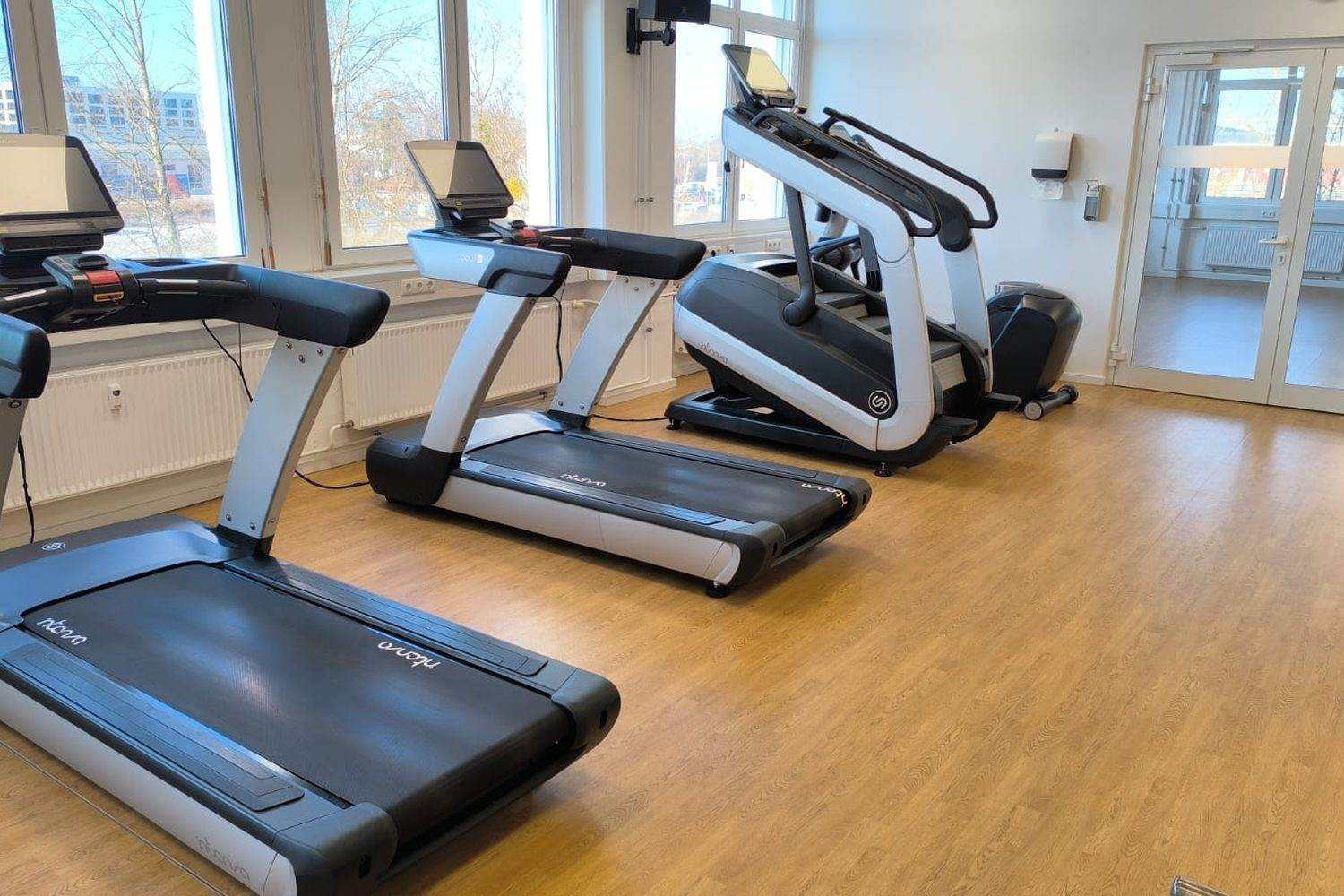 Salle de fitness au Luxembourg avec une rangée de tapis de course et un escalier ergomètre